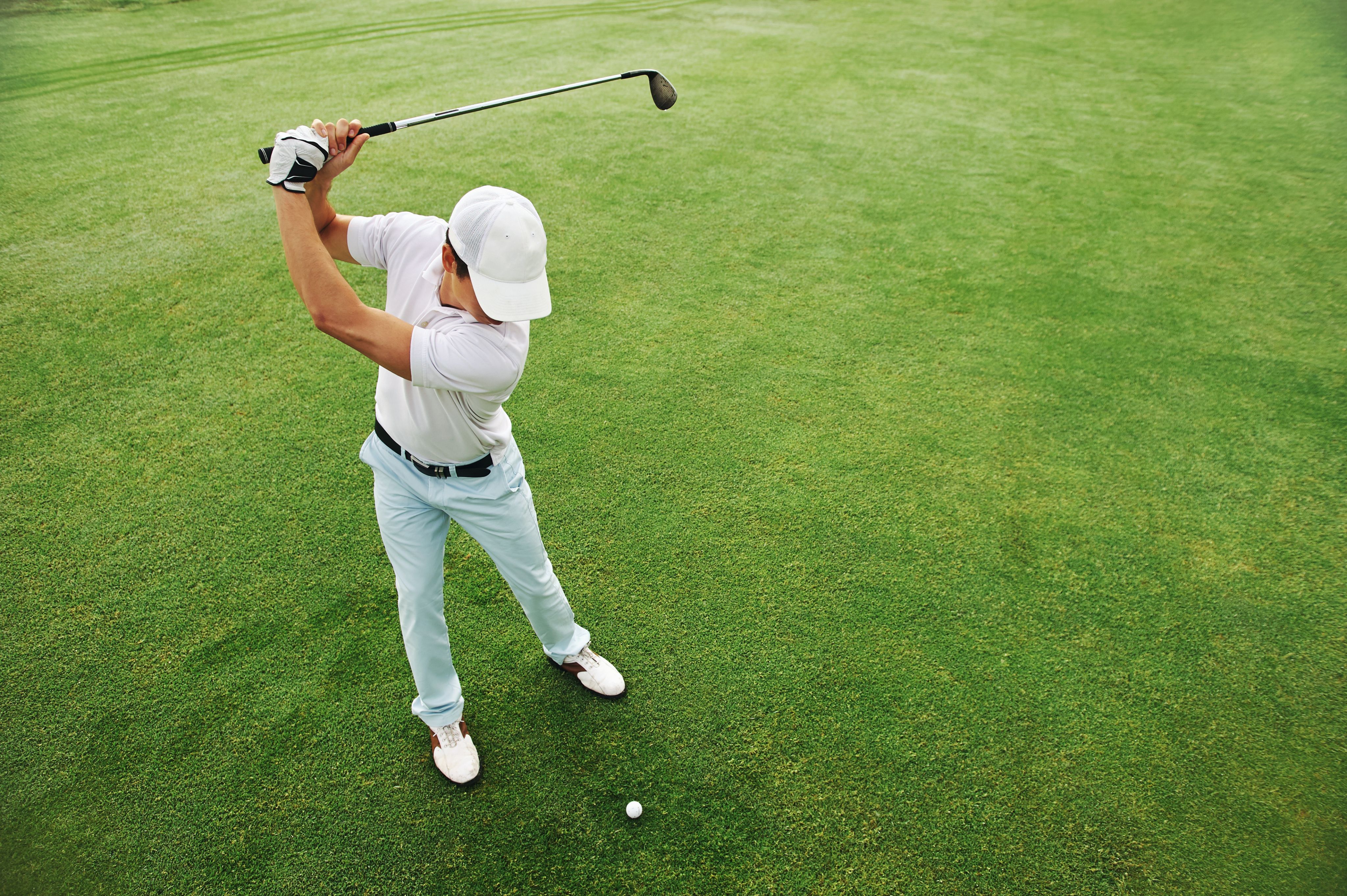 Man mid-swing on a sunlit golf course, showing the vitality peptide therapy supports.
