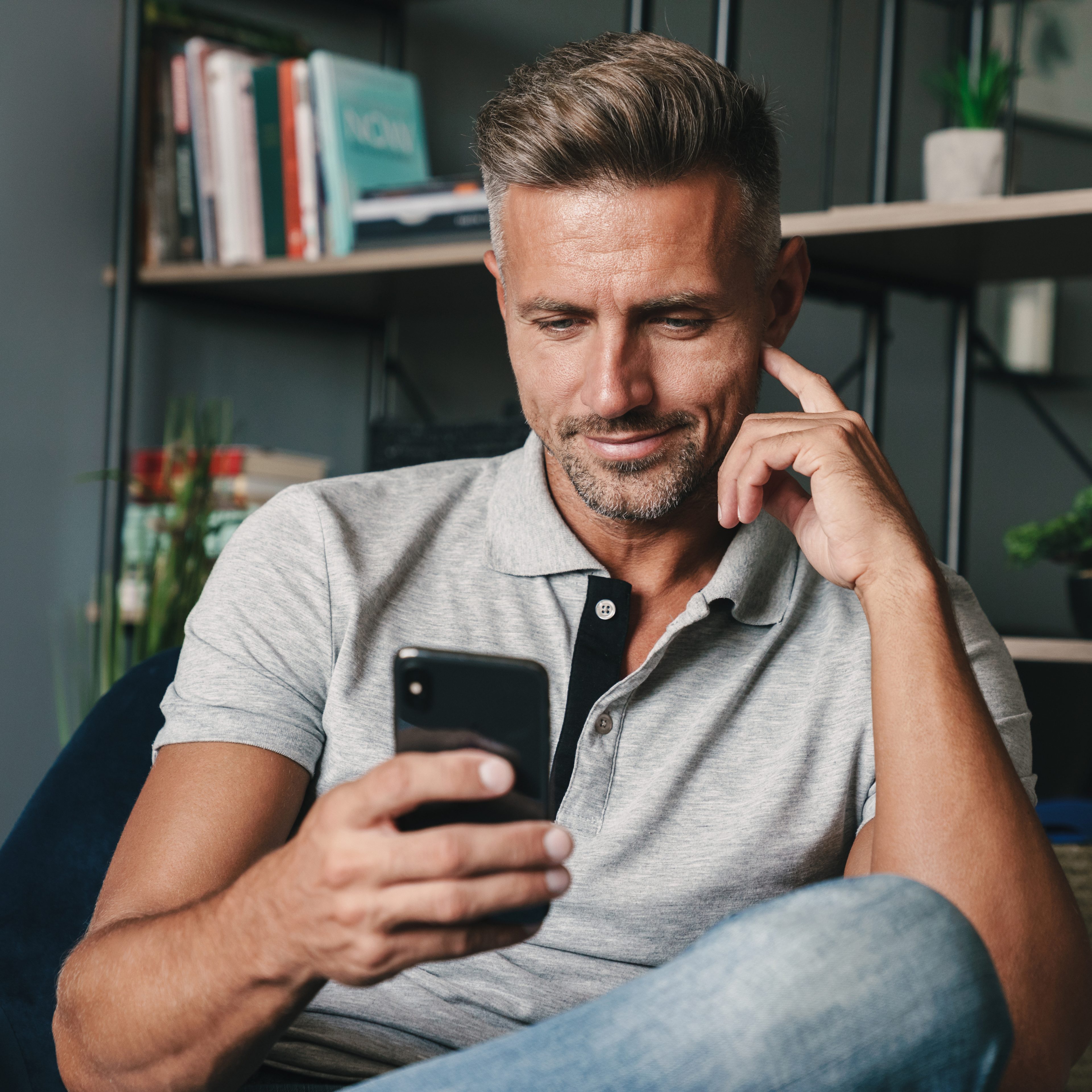 Man relaxing at home with phone — initial consultation imagery.